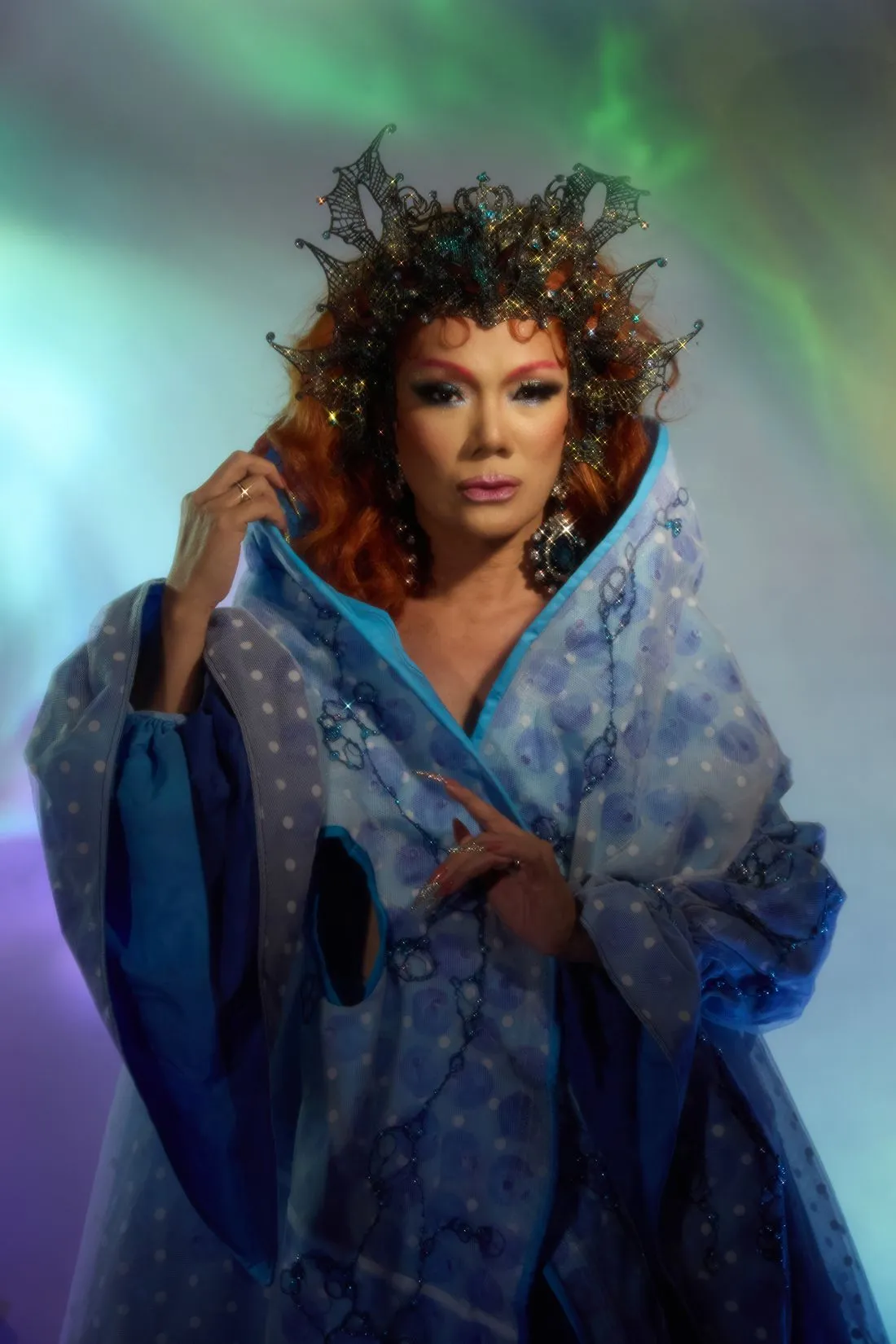 A Heals queen in a jewelled lace crown and a blue polka-dot cloak