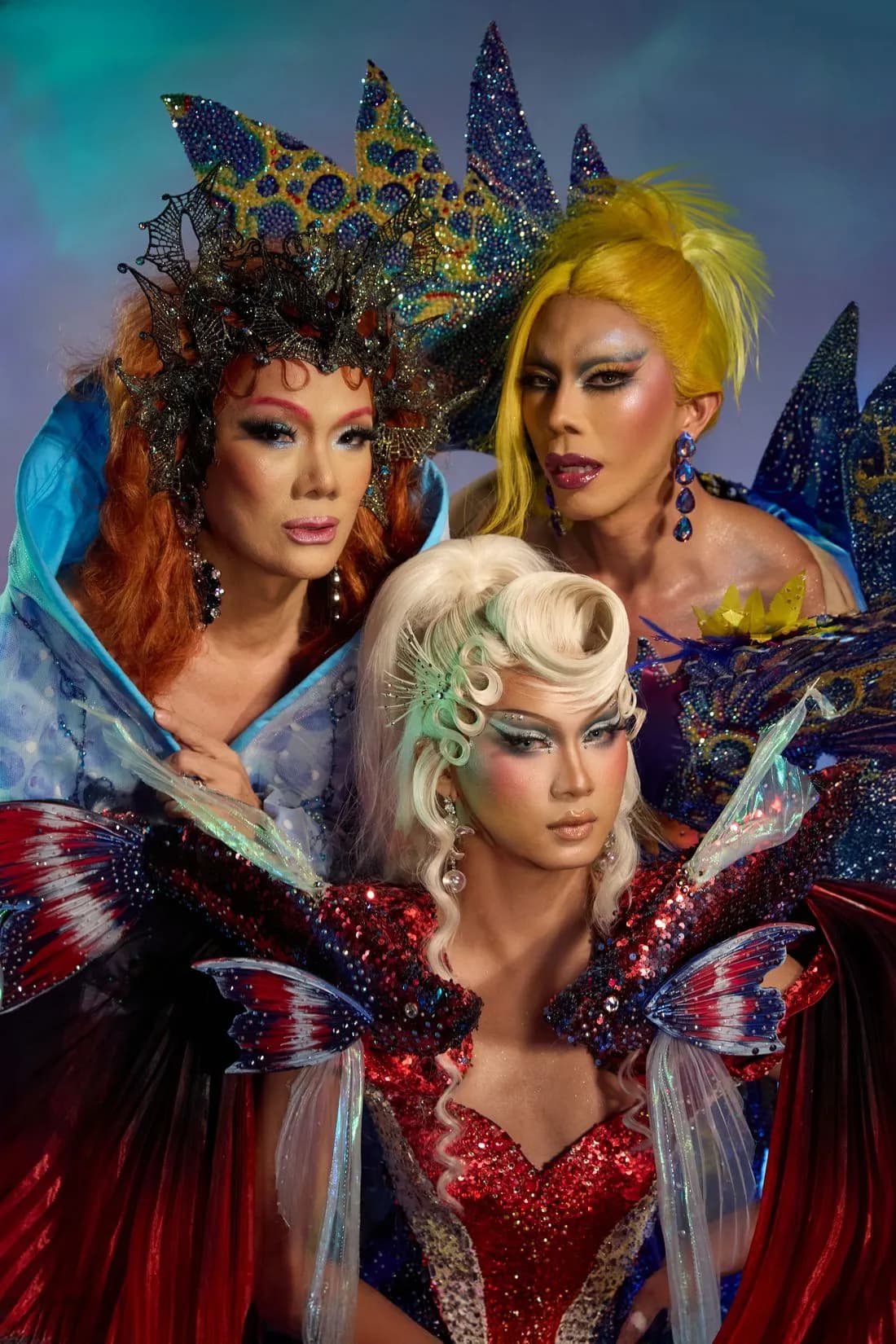 Three Heals queens in full drag: crowns, fins and sequins